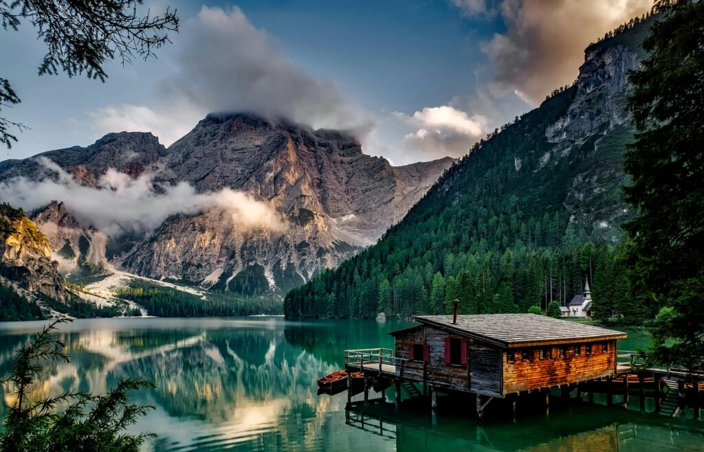 italy-mountains-dawn-daybreak-147411-147411 Peaceful mountain lake scene featuring a rustic boathouse and stunning reflections.